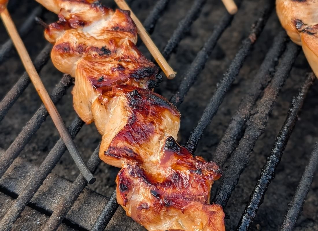 Espetinhos de frango dourando na grelha